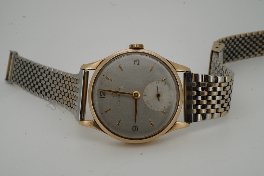 A gentleman's late 1940's 9ct gold Omega manual wind wrist watch, with baton and quarterly Arabic numerals and subsidiary seconds, movement c.265, case diameter 33mm, no logo on winding crown, on an associated stainless